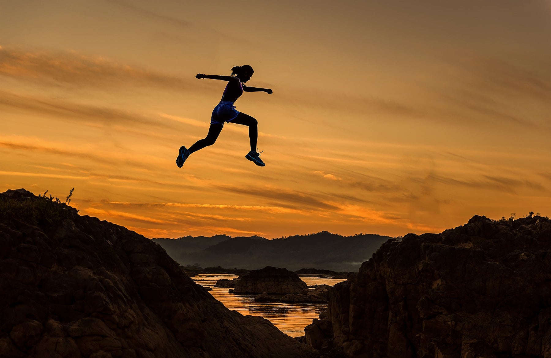 Woman jumping over hills during an evening