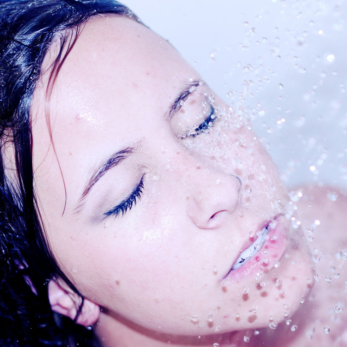 Brunette woman taking a shower with eyes closed