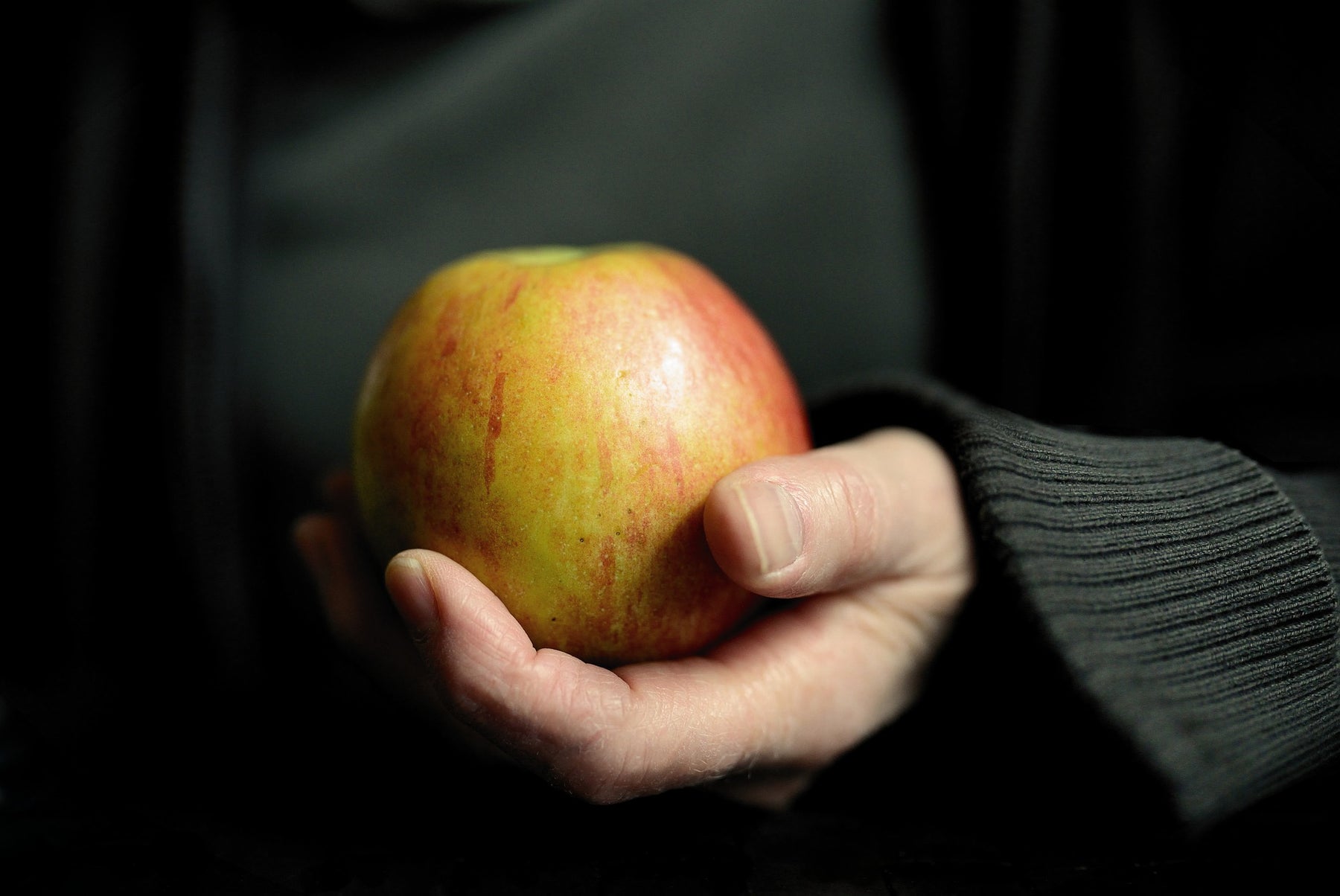 Person wearing black holding an apple in their hand