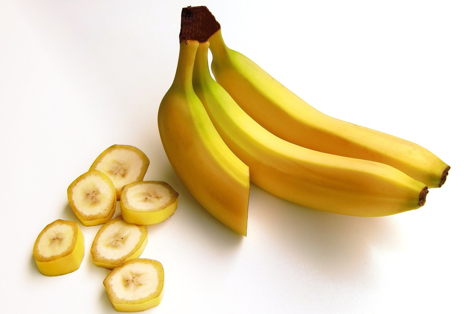Three bananas one cut in half and sliced