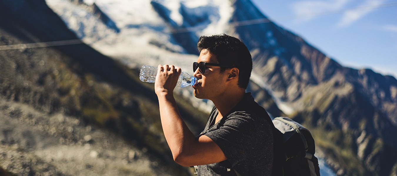 Thirsty man with black t-shirt and black backpack drinking water and hiking