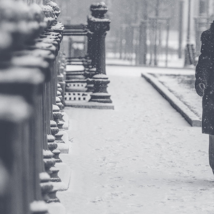 Woman walking down the street in a cold winter while snowing
