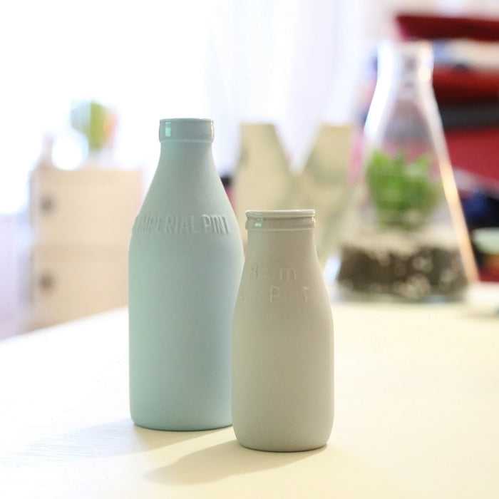 Two bottles of milk laying on a wooden table