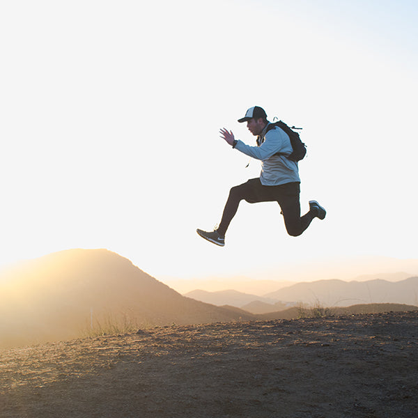 Man with backpack jumping over mountains