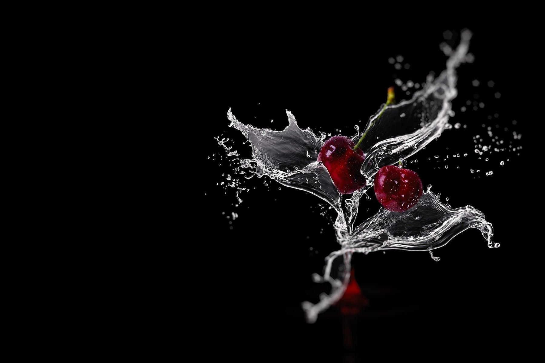 Two cherries with a splash of water on a black background