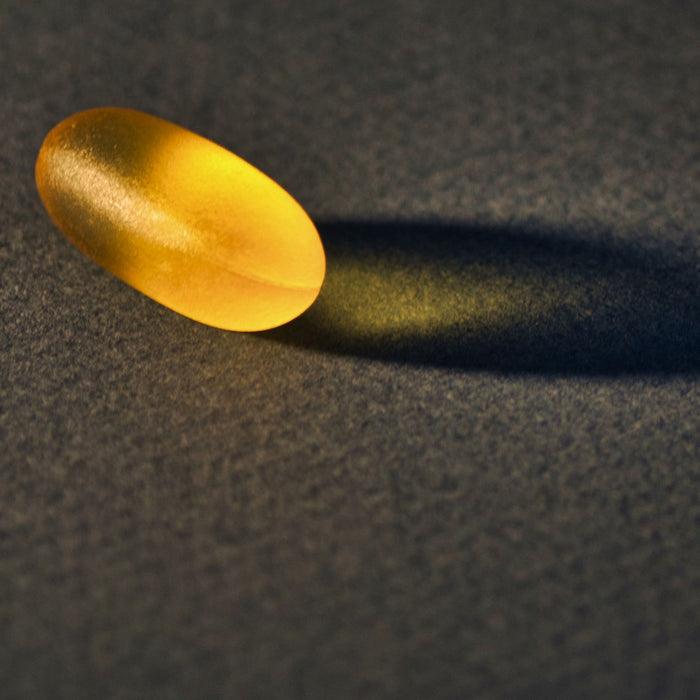 On pill and its shadow on a black surface