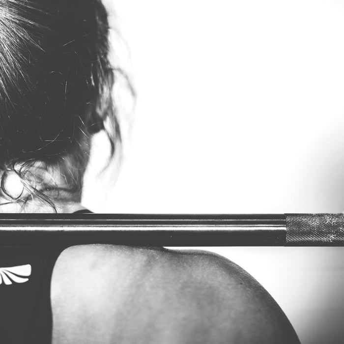 Woman holding barbell over the shoulders