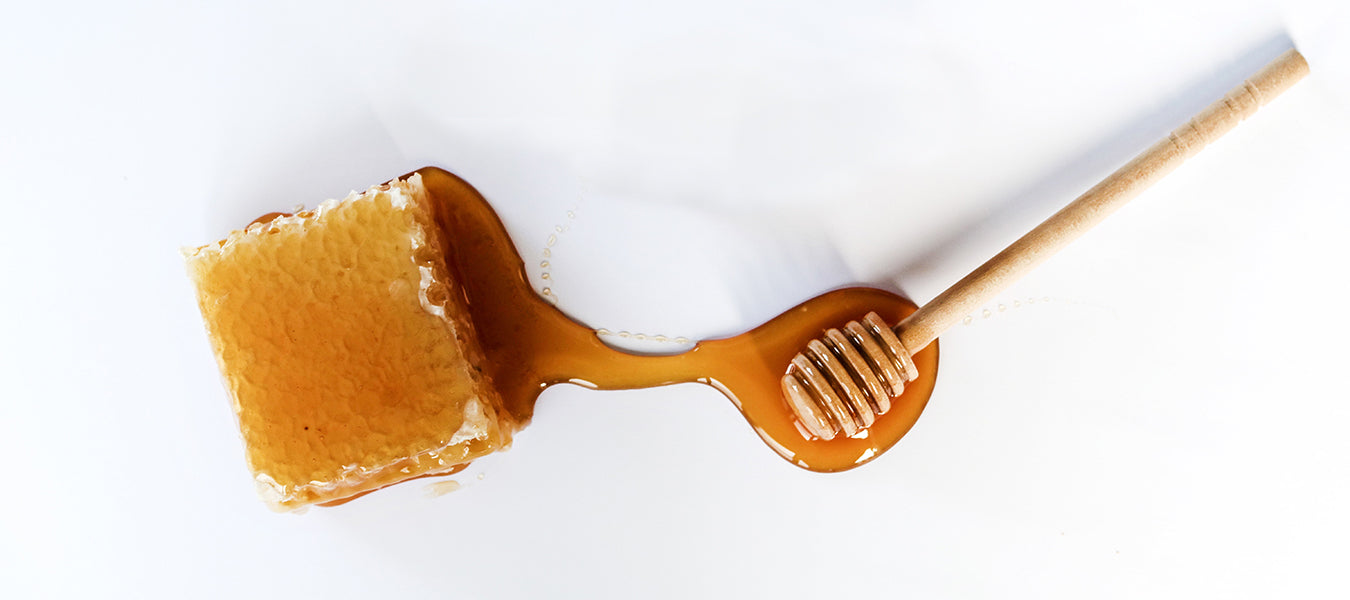Raw honey along with honey stick on a white background