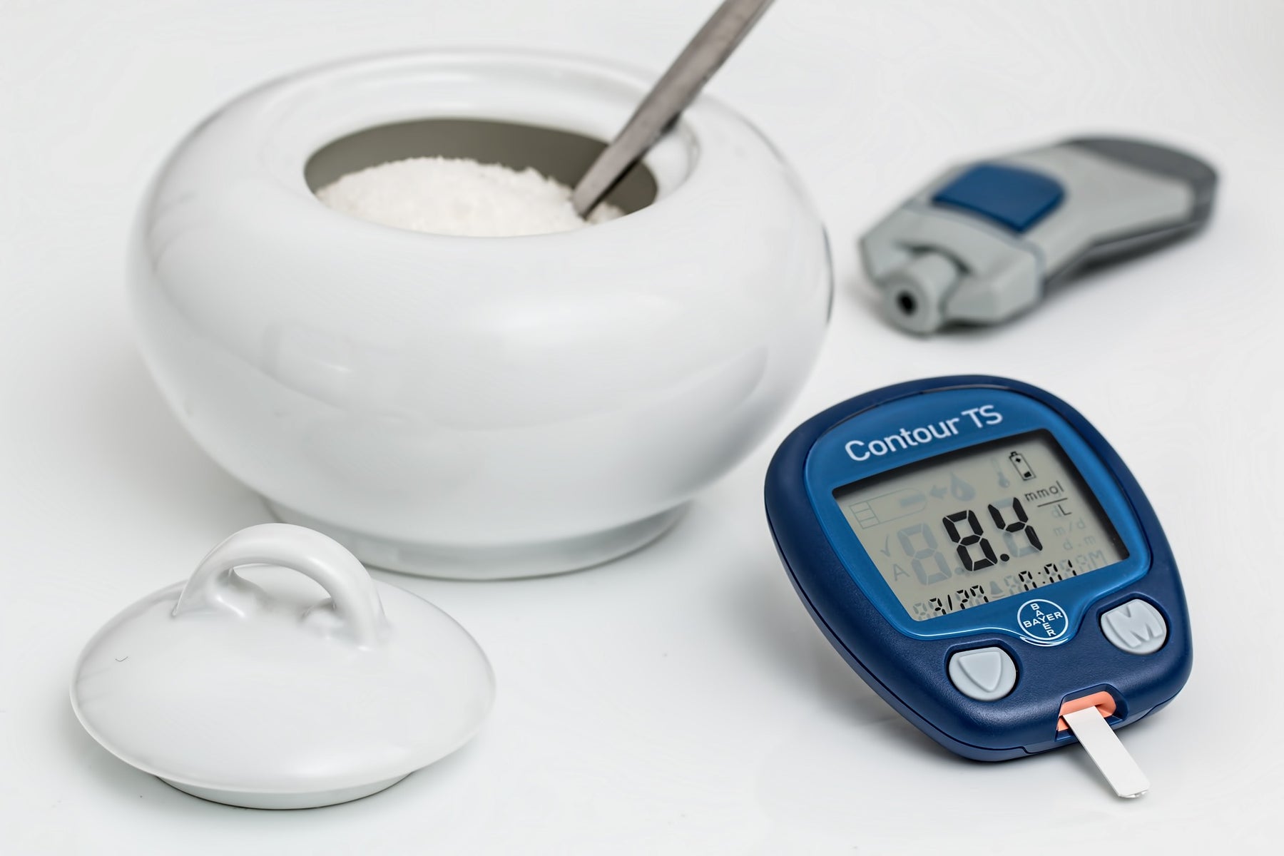 A digital measurement next to a white bowl of sugar