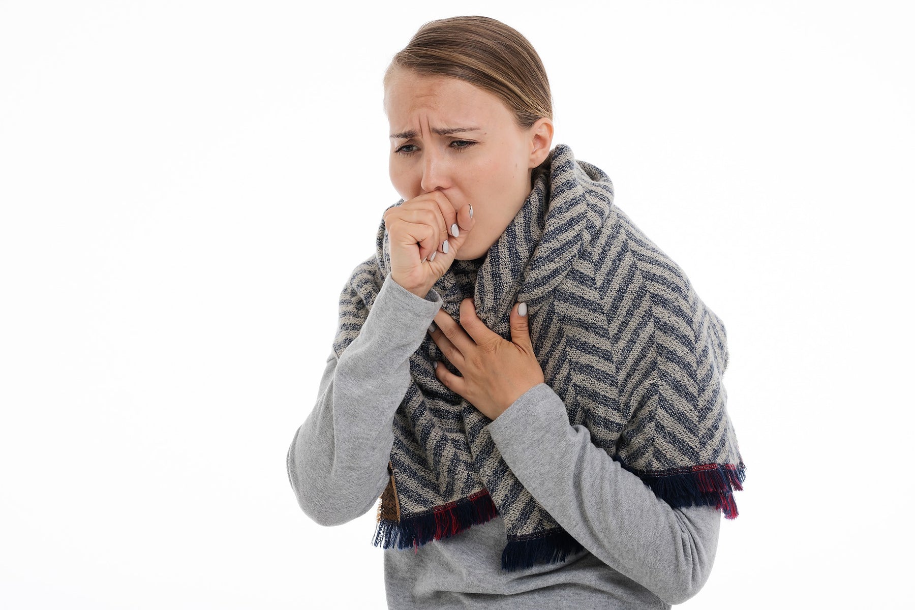 Woman in grey coughing with her hand over mouth