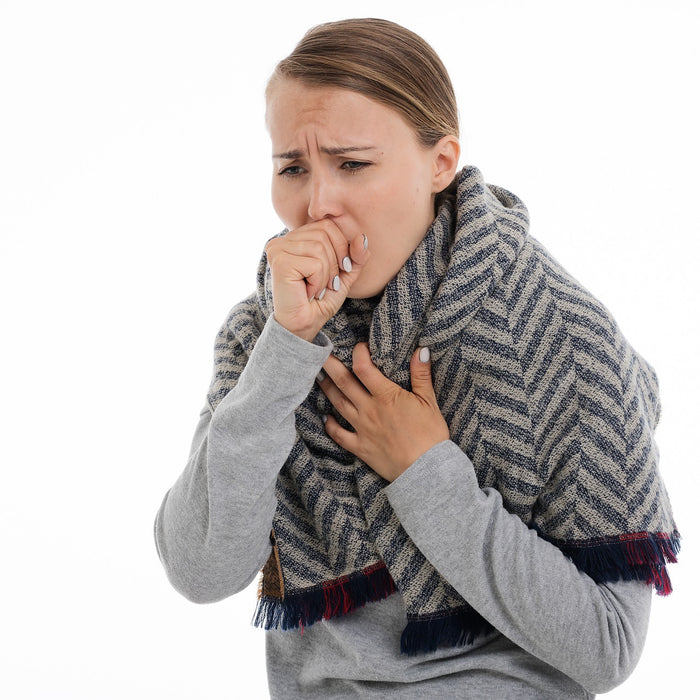 Woman in grey coughing with her hand over mouth