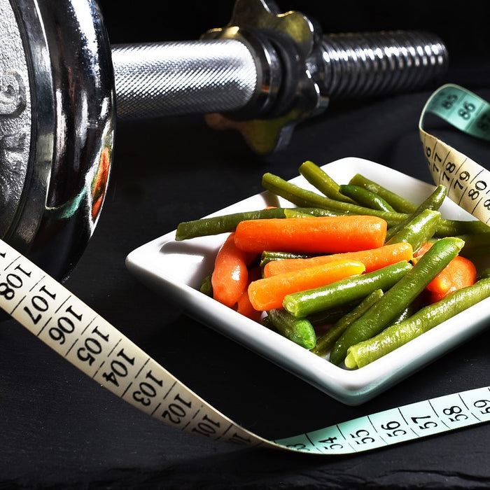 Dumbell next to a plate of vegetables and a ruler