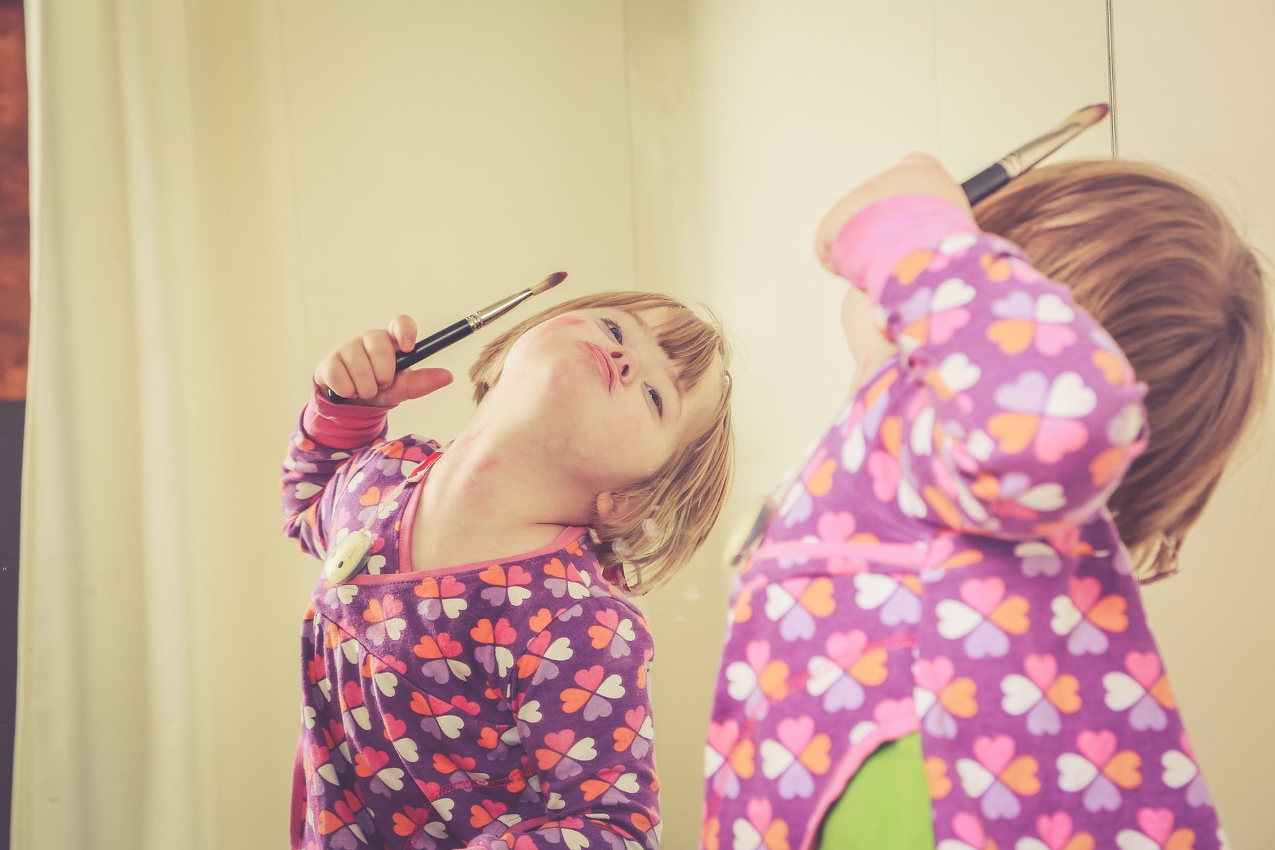 Girl in pajamas making faces in the mirror