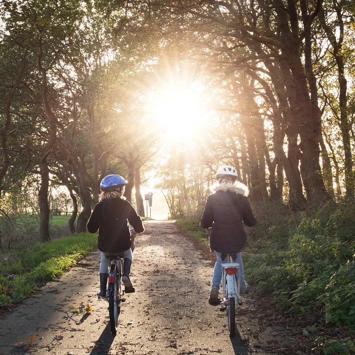 Two kids on a bicycle in the forest