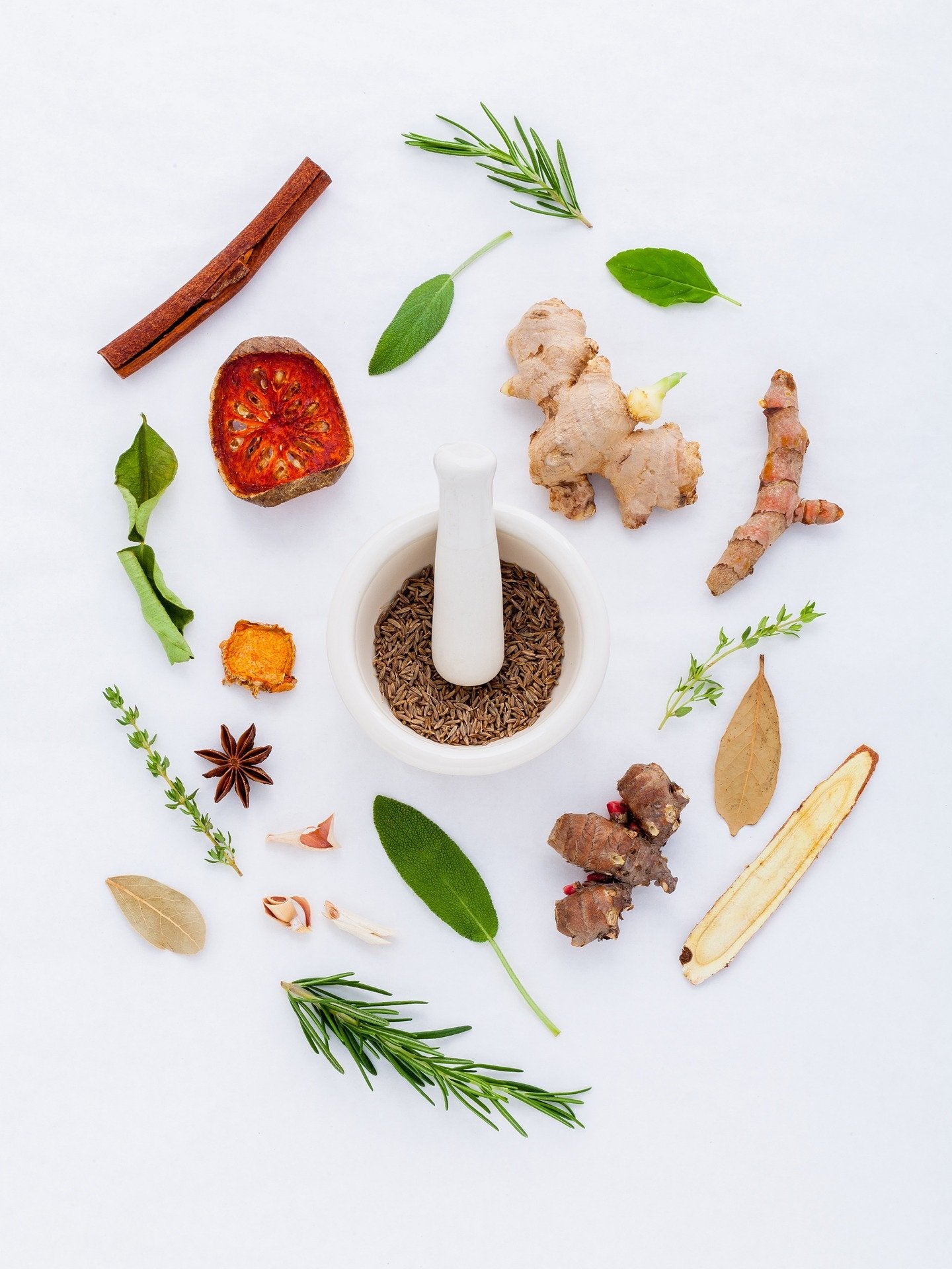 Roots and herbs surrounding a small bowl of caraway