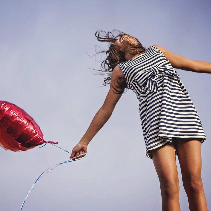 Happy girl in dress holding a red balloon