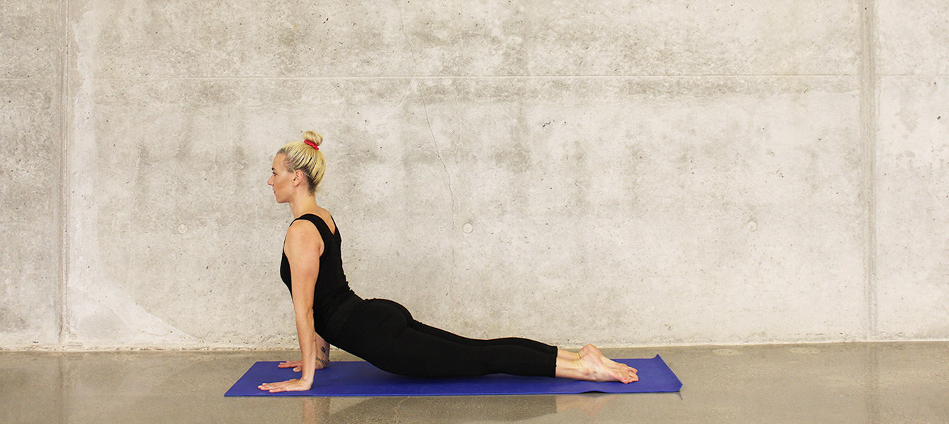 Blonde woman dressed in black doing yoga on a blue yoga mat