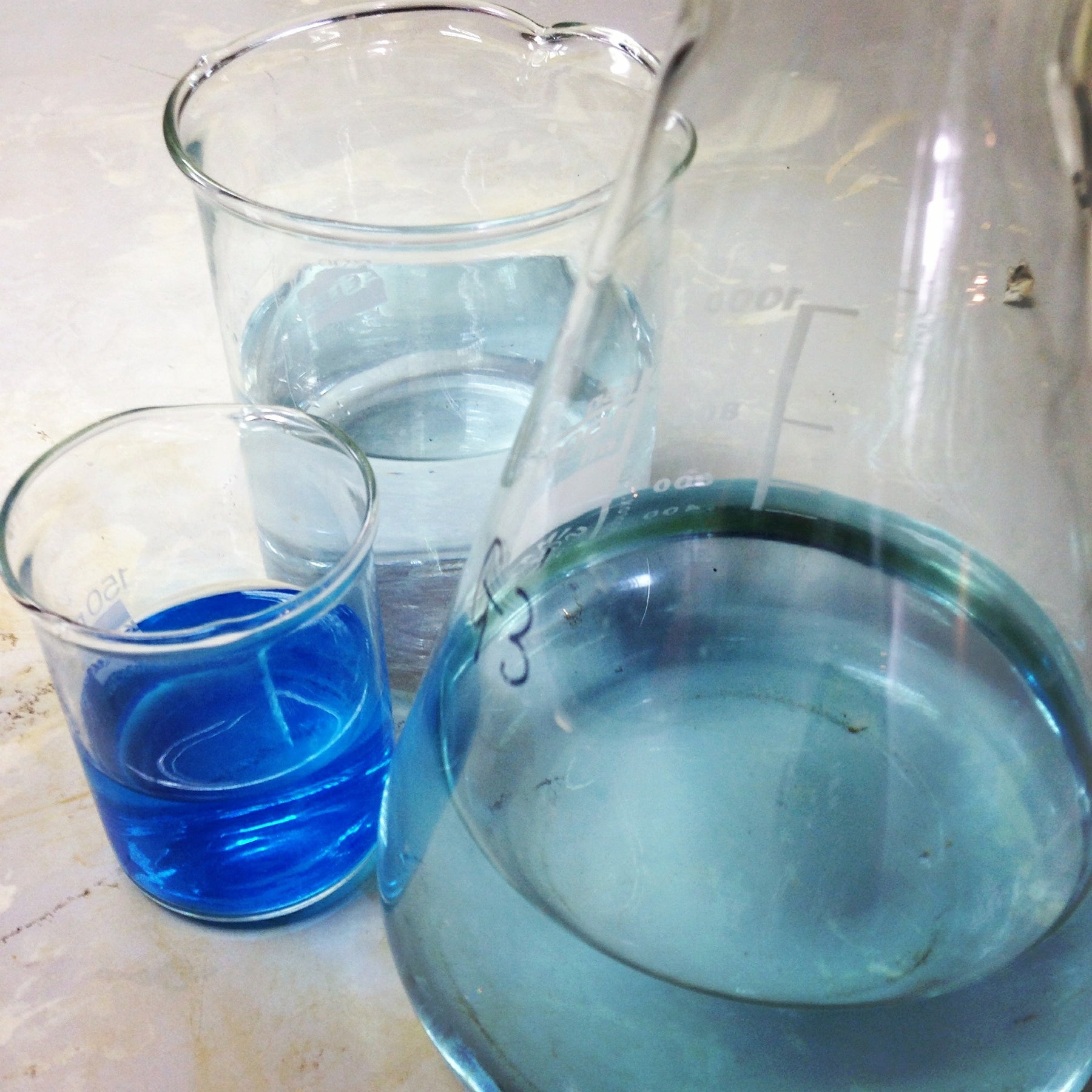 Three glass containers with blue liquid