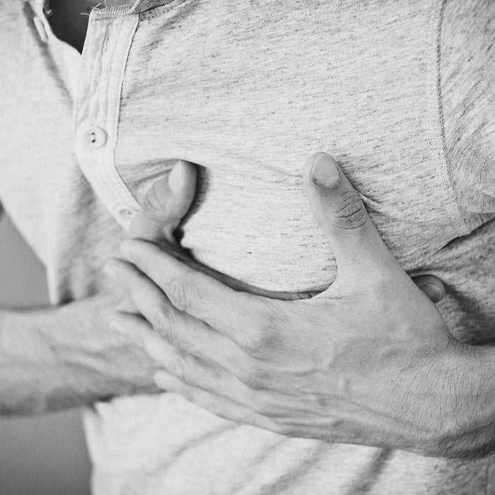 Man in t-shirt holding his chest in pain with both hands