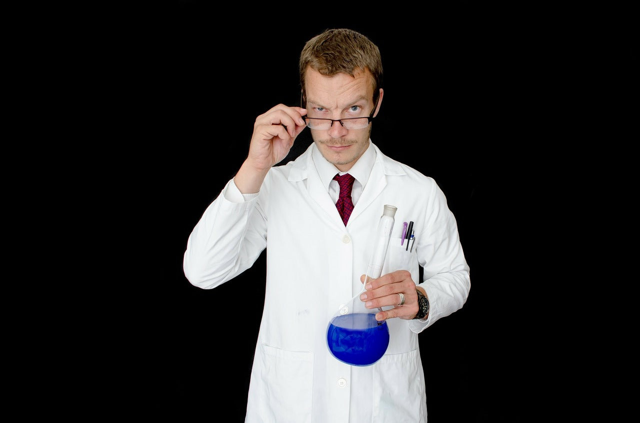 Laboratory man holding his glasses and a glass recipient with blue liquid