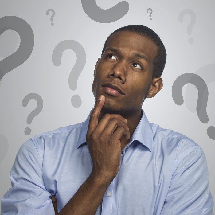Man in a shirt with his head up thinking surrounded by question marks