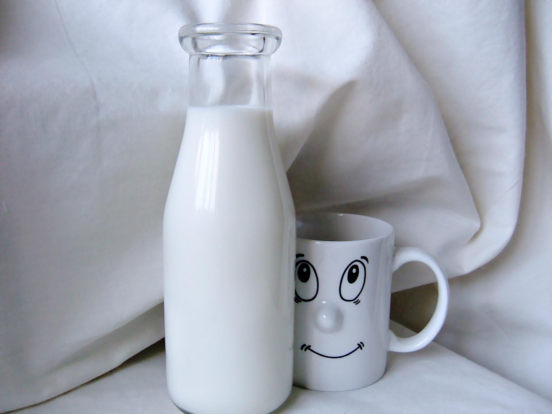 Bottle of milk next to a cup with a face drawn on it