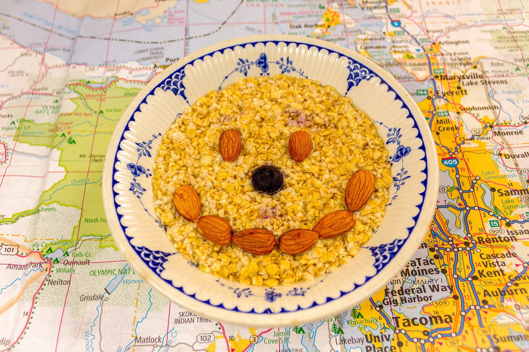 A bowl of outmeal with a smiley face made from almonds