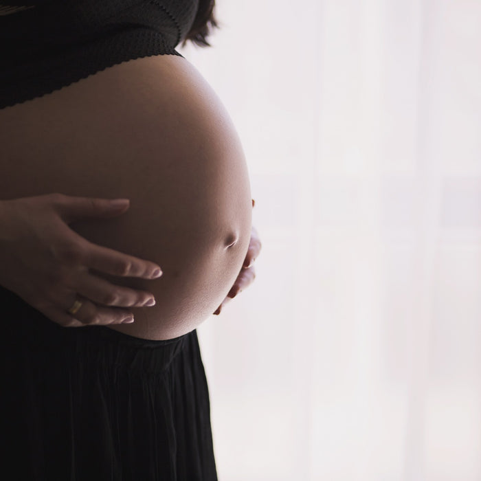 Pregnant woman wearing black with hands over the belly