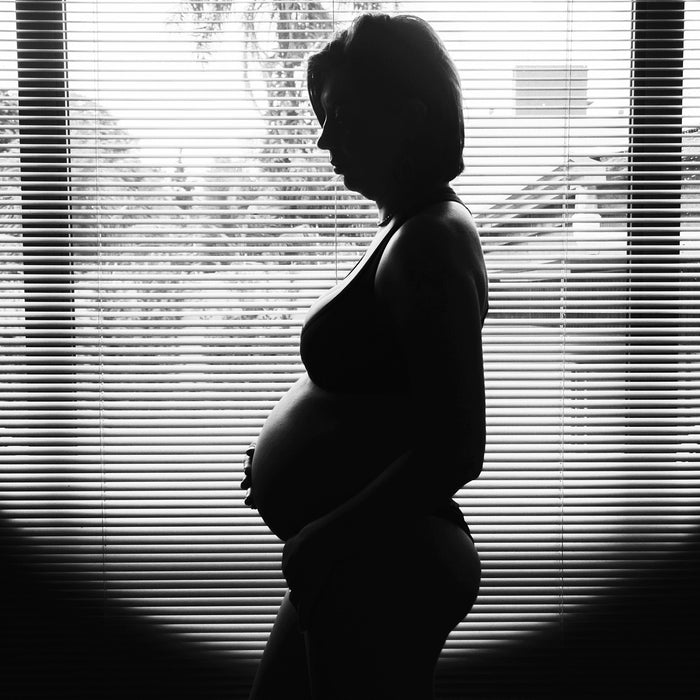 Pregnant woman sitting in a dark room with windows in the middle