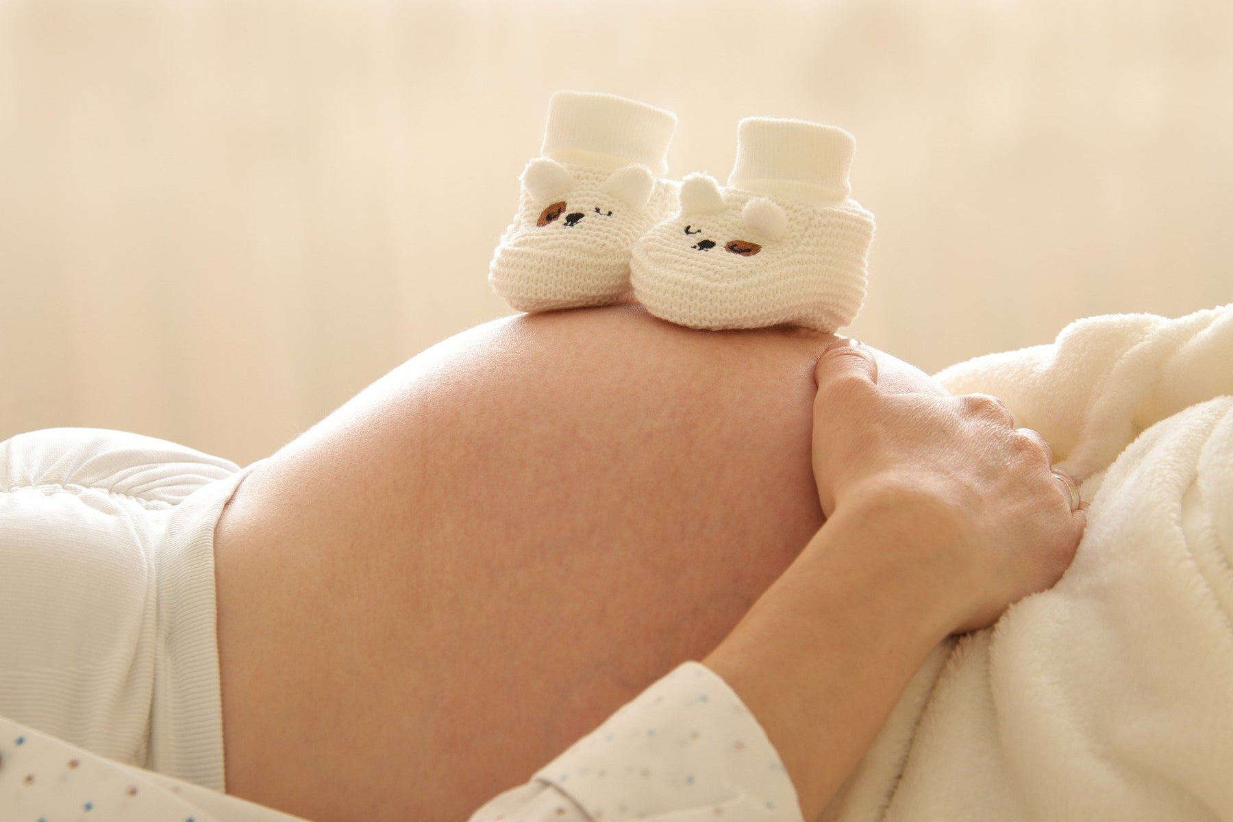 Pregnant woman's belly with socks-like shoes sitting on top of the belly
