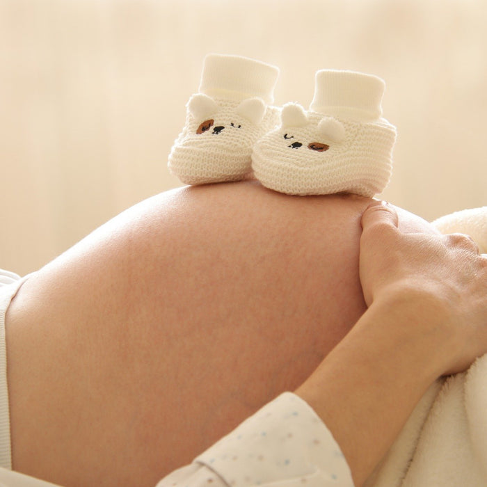 Pregnant woman's belly with socks-like shoes sitting on top of the belly