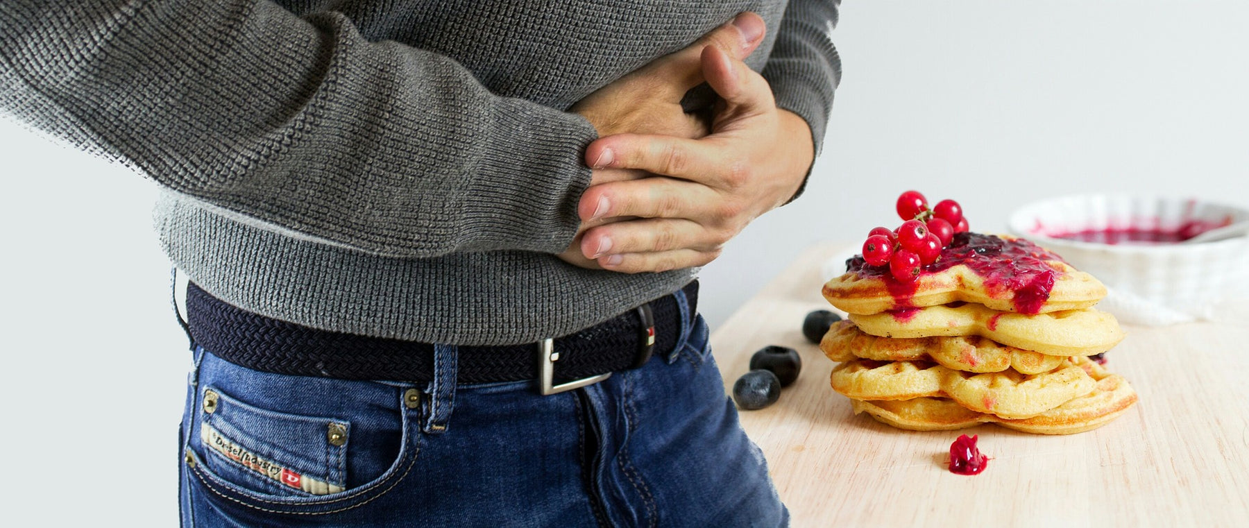 Man in sweater and jeans expressing stomach pain