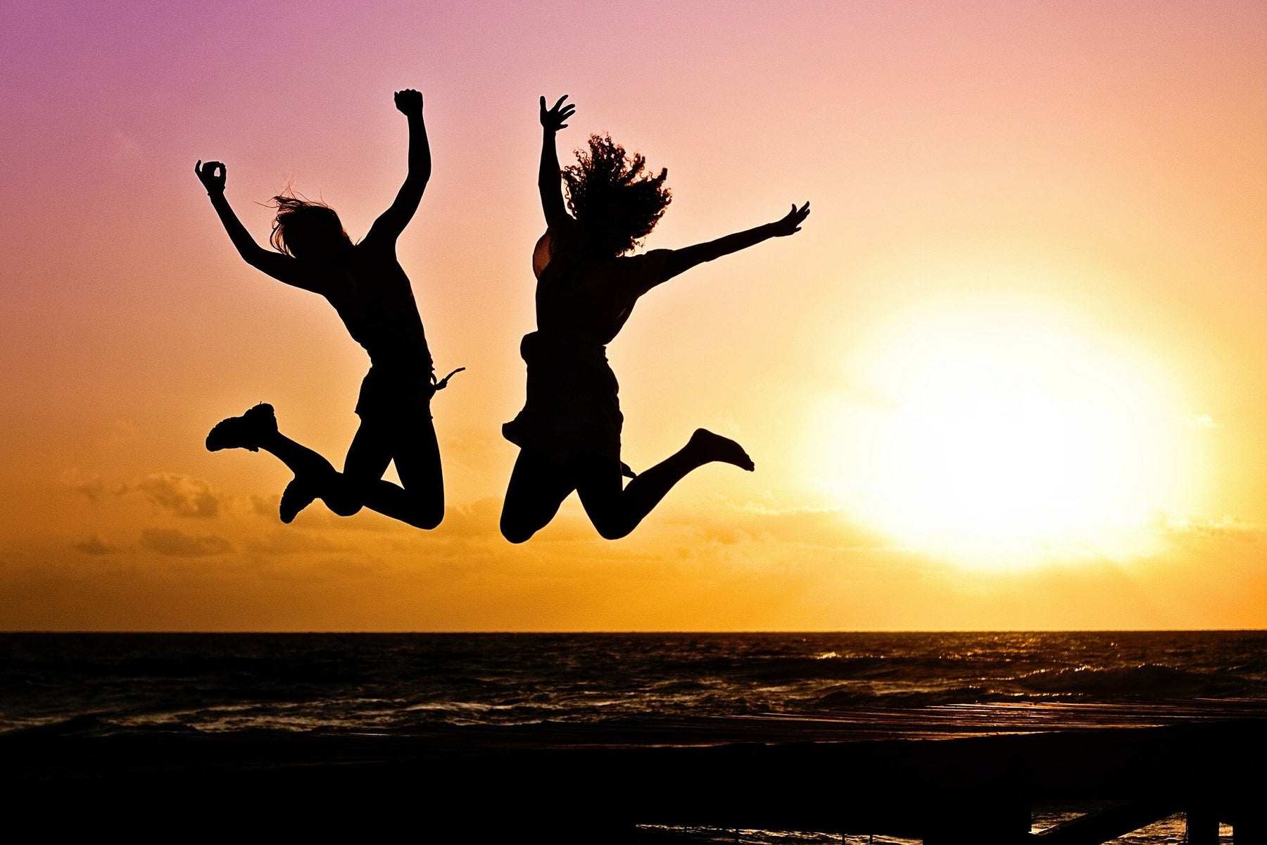 Women jumping at a sunset over the beach