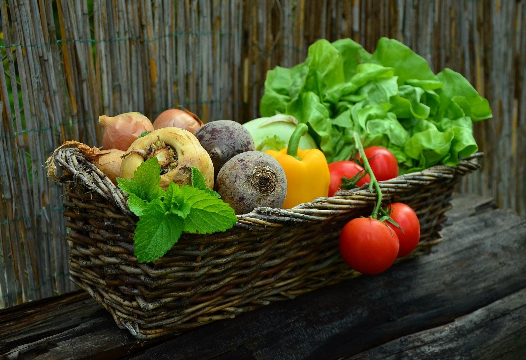 Basket full of vegetables, including tomato and bell papers