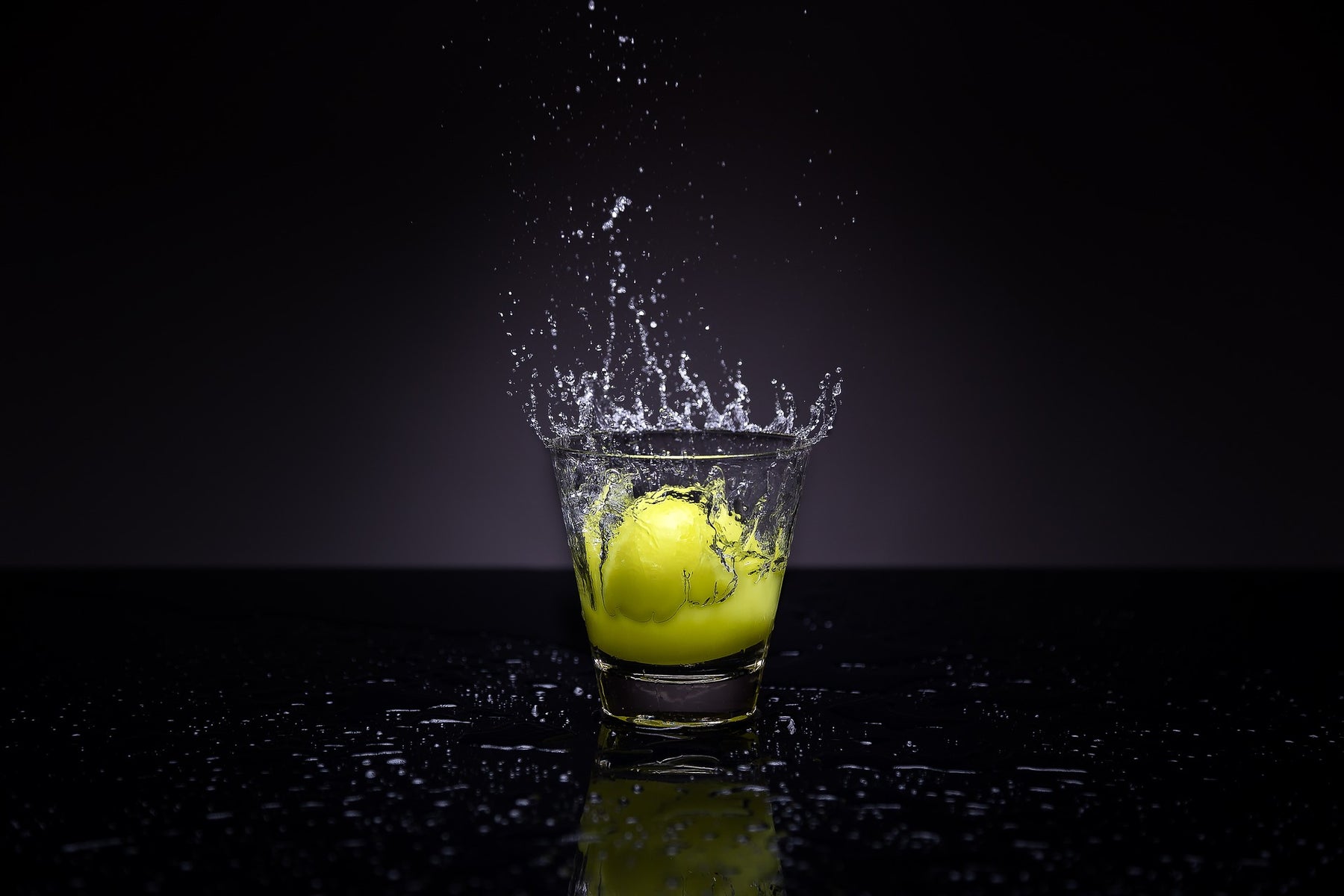 Lemon thrown in a glass of water over a black background