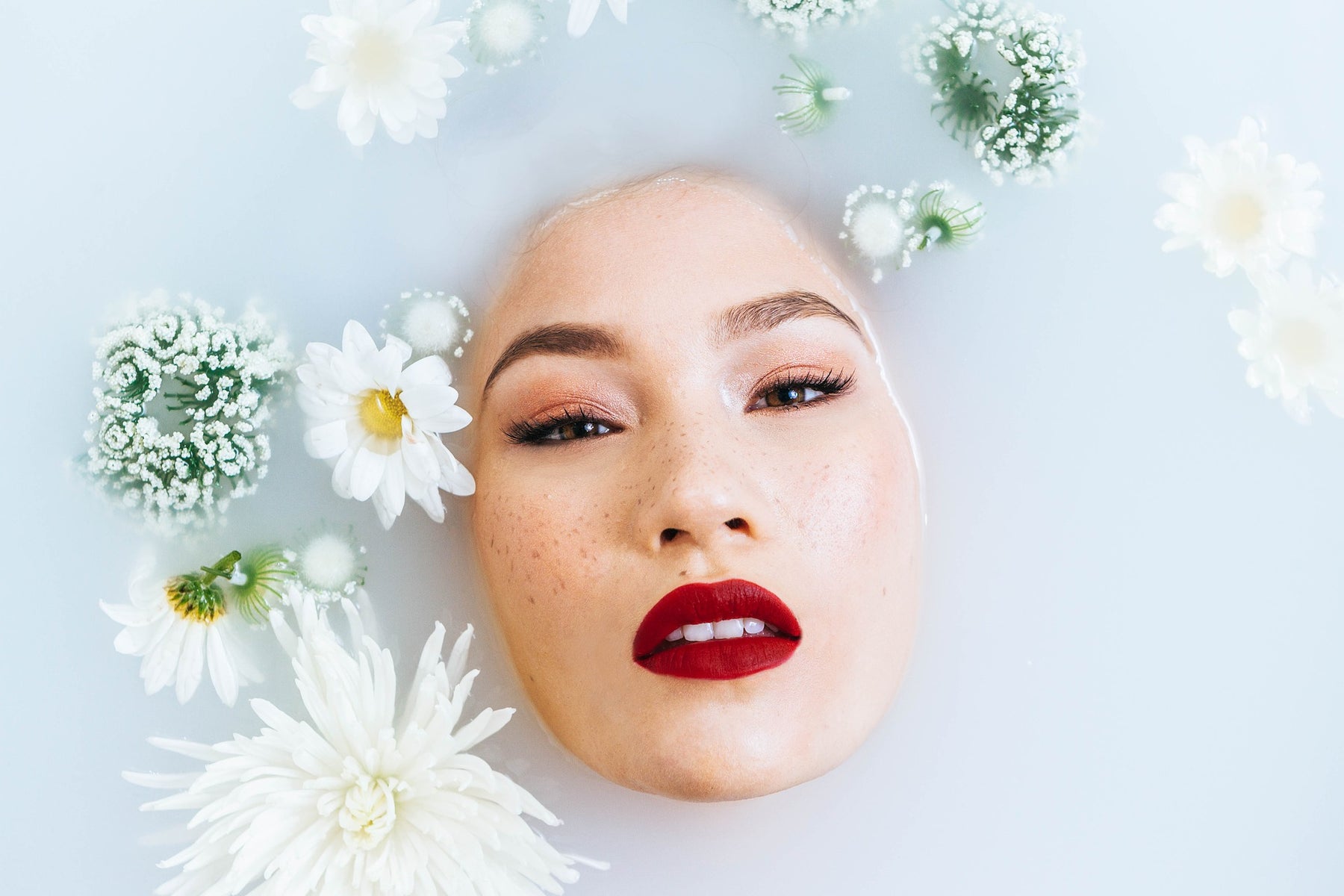 Woman with red lips covered by water and plants