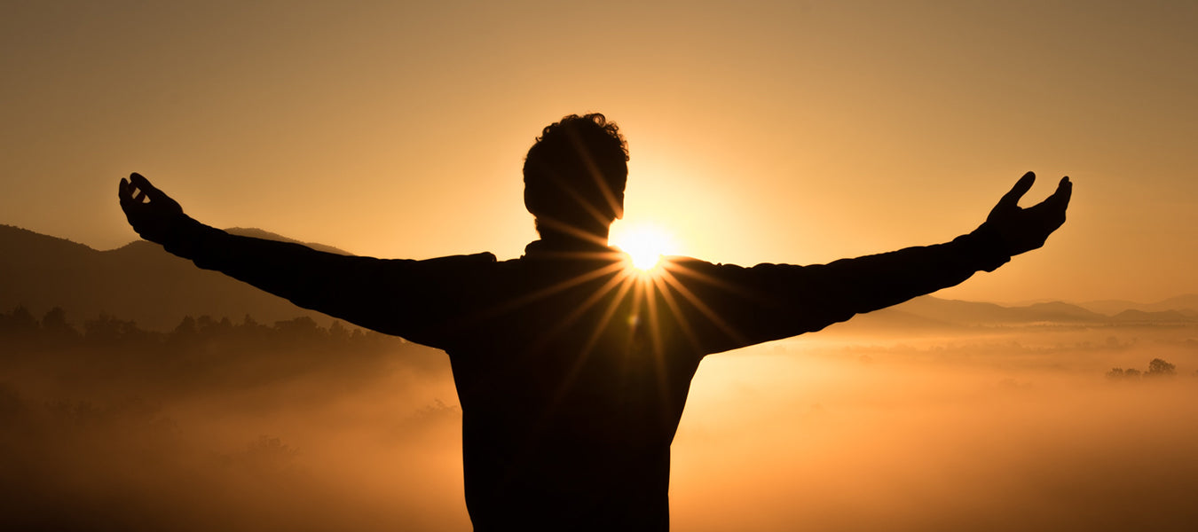 Man enjoying sunset with hand raised